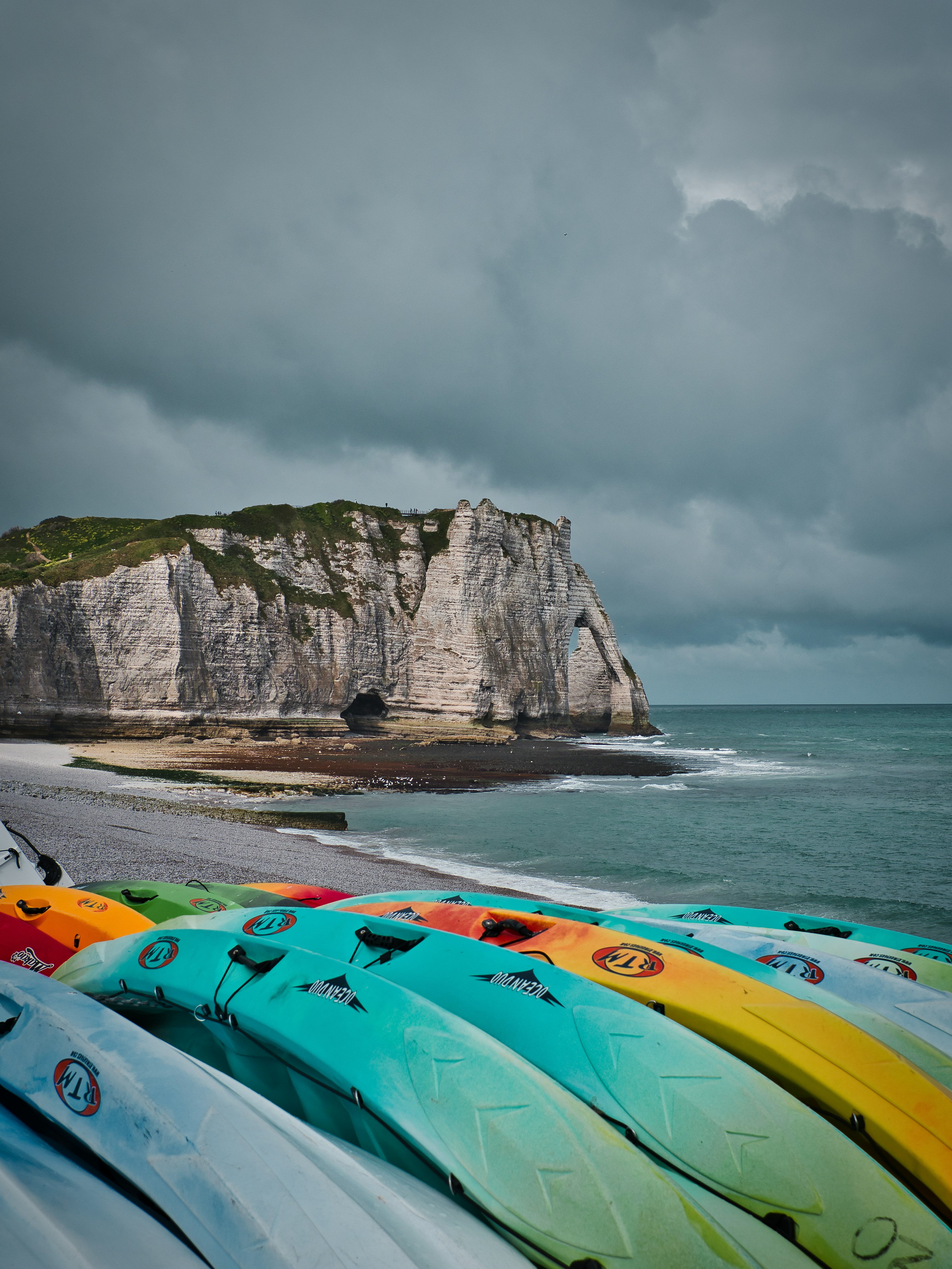 Green and yellow kayak on sea shore near mountain under cloudy sky during daytime
