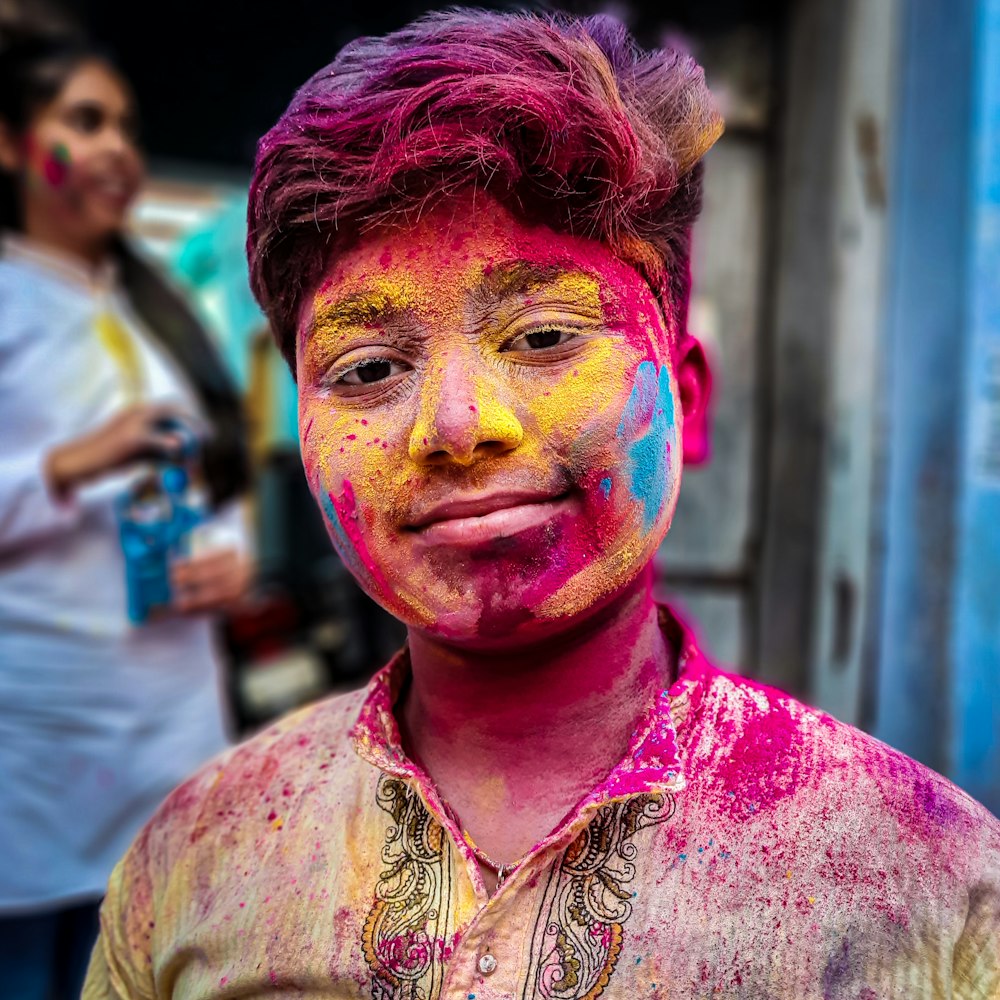 woman in purple and brown floral button up shirt with pink and blue powder on face