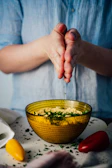Chef sprinkling fresh herbs over a traditional Brazilian dish in a cozy kitchen
