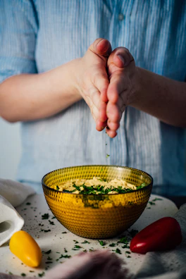 Chef sprinkling fresh herbs over a traditional Brazilian dish in a cozy kitchen