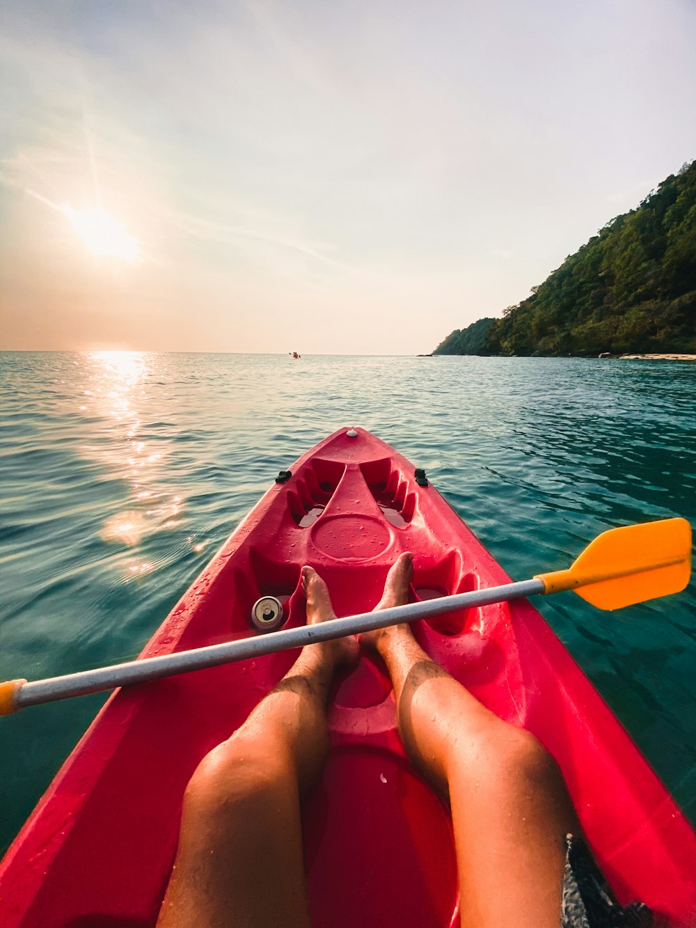 woman in red bikini riding on red kayak on sea during daytime