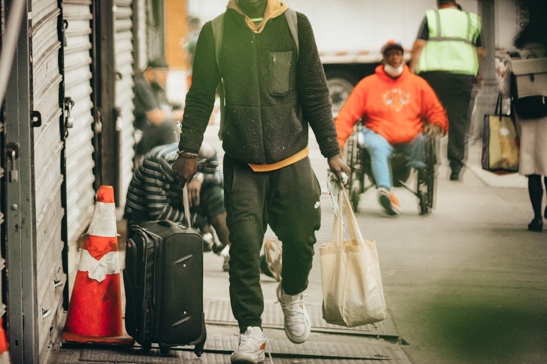 man in black and green long sleeve shirt holding white plastic bag