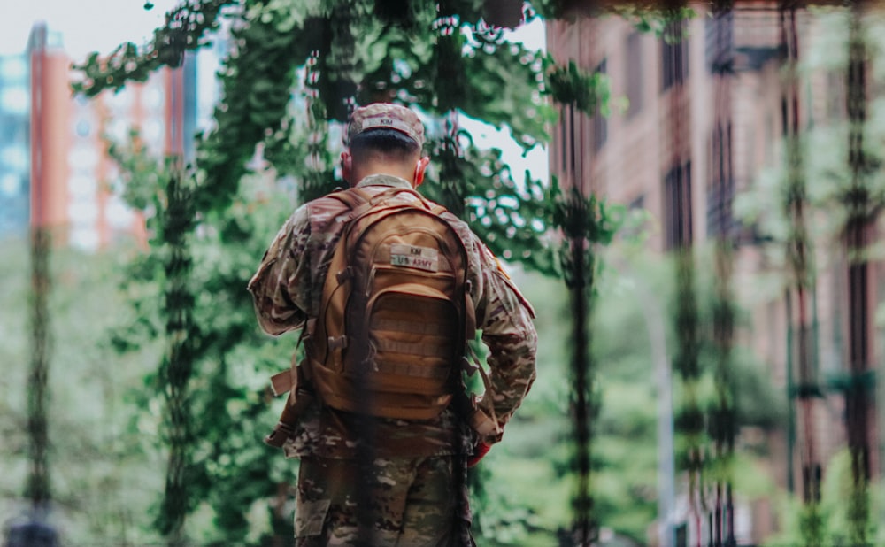 man in brown and black camouflage jacket standing in forest during daytime