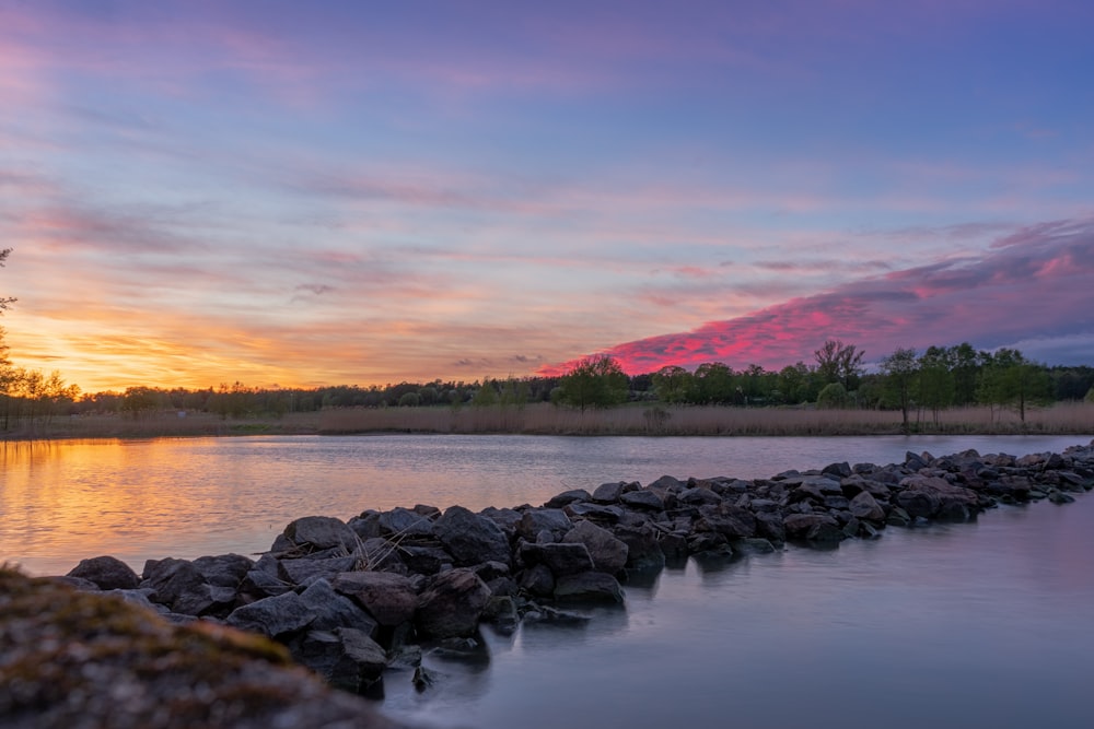 gray rocks on body of water during sunset