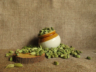 Fresh green cardamom pods spilling from a woven basket onto a rustic table.