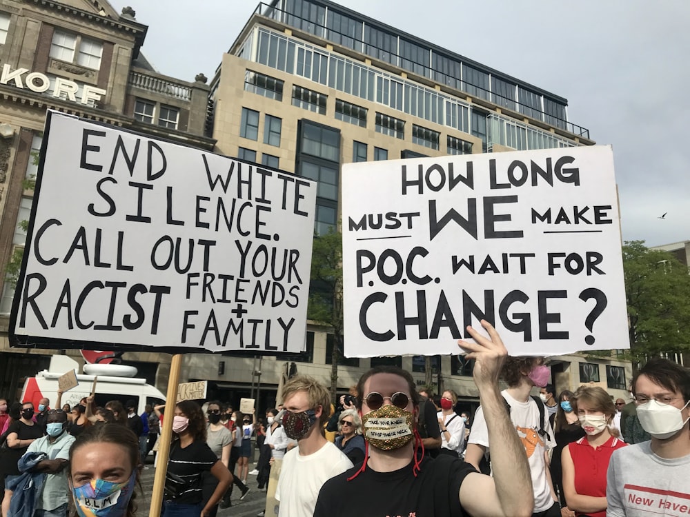 group of people holding white and black signage