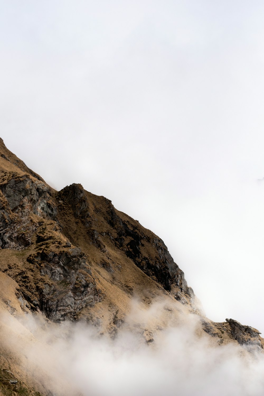 Montagna rocciosa marrone sotto il cielo bianco durante il giorno