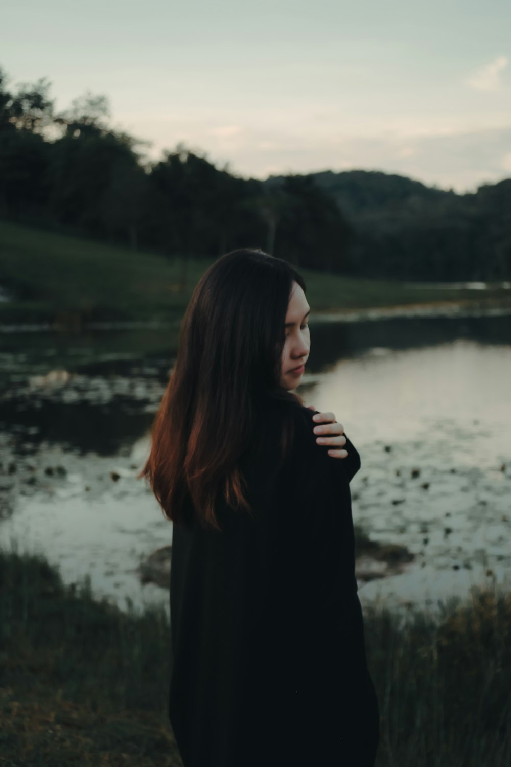 woman in black long sleeve shirt standing near lake during daytime