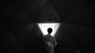 grayscale photo of man in white shirt standing