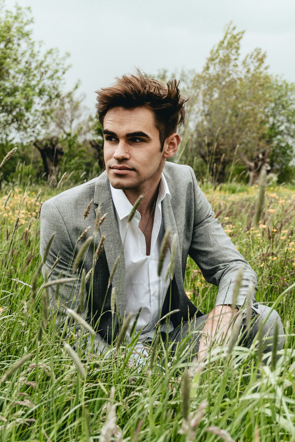 man in gray suit jacket sitting on green grass during daytime