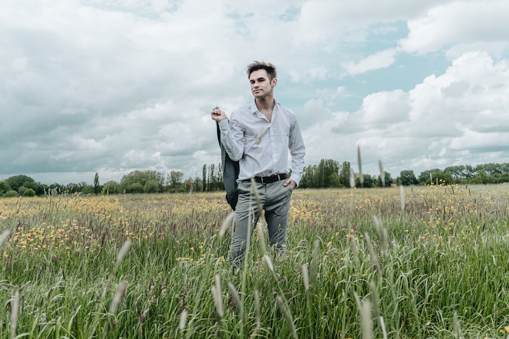man in gray dress shirt standing on green grass field during daytime