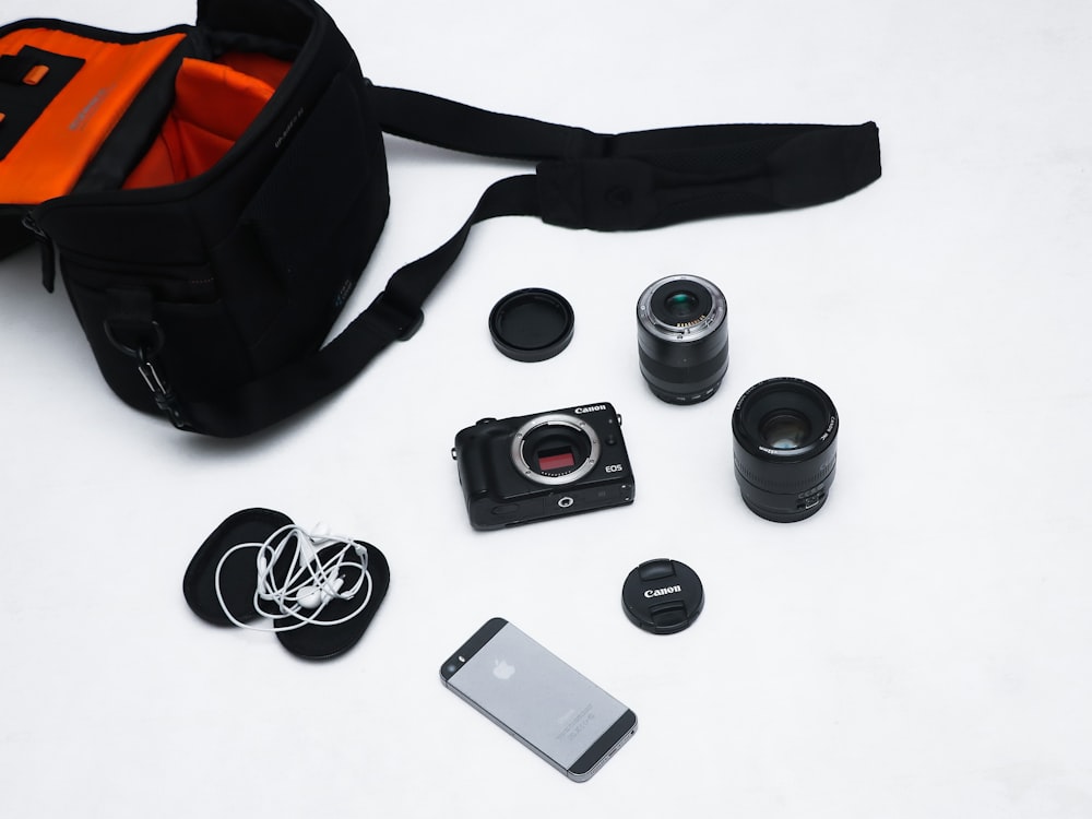 black and red backpack beside black and silver camera