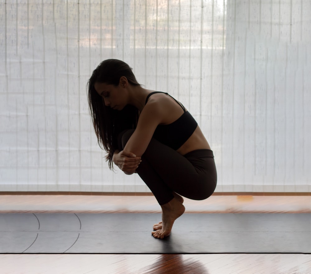 woman in black tank top and black leggings kneeling on floor