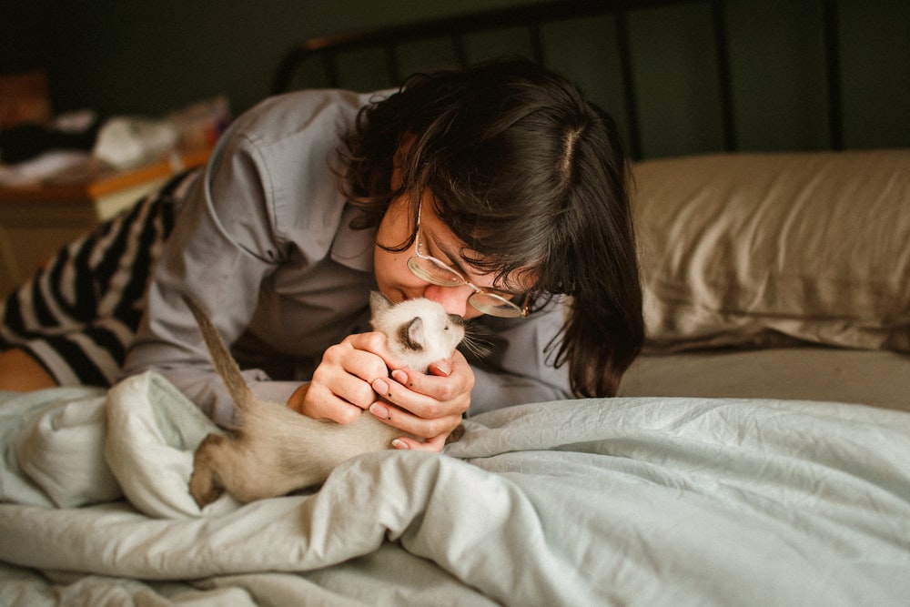 a woman is petting a cat on the bed