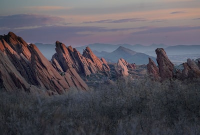 brown rocky mountain under white clouds during daytime surreal teams background