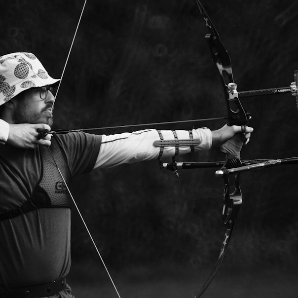 man in black shirt and brown pants holding bow