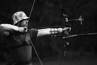 man in black shirt and brown pants holding bow