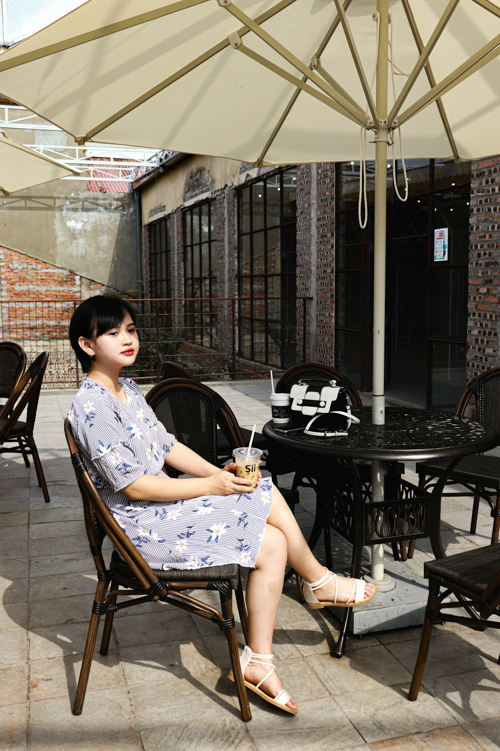 woman in white and blue floral dress sitting on brown wooden chair