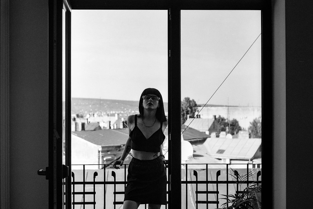 woman in black tank top and black pants standing beside glass window