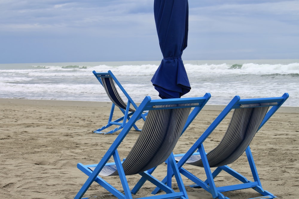 낮 동안 해변에 파란색과 검은 줄무늬 접이식 의자