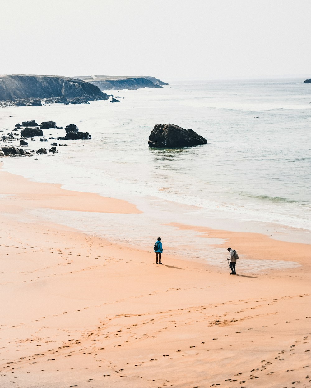 2 people walking on beach during daytime