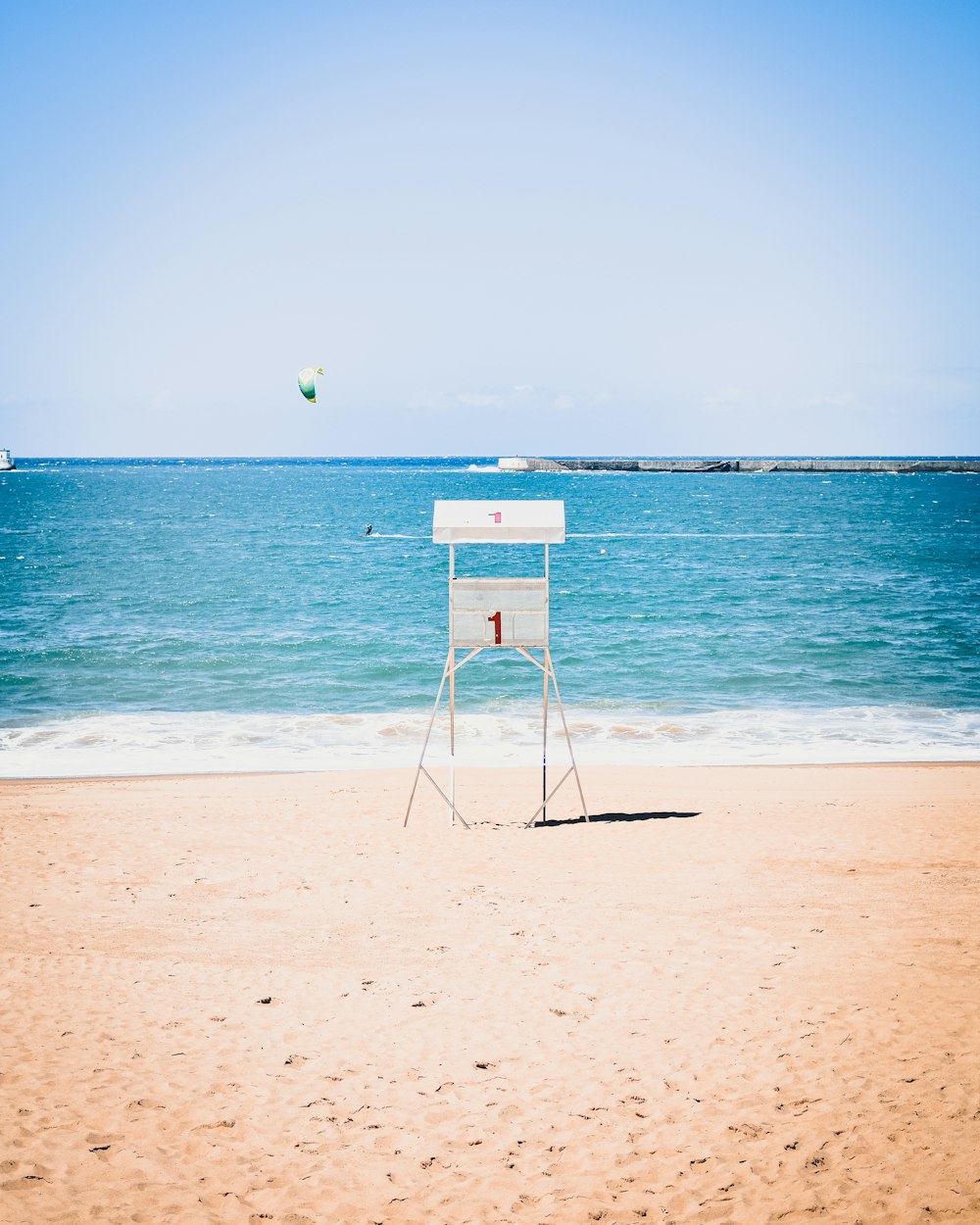 Silla de socorrista de madera blanca en la orilla de la playa durante el día