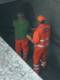 2 men in orange and green jacket