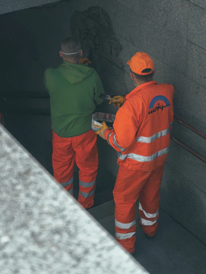 2 men in orange and green jacket