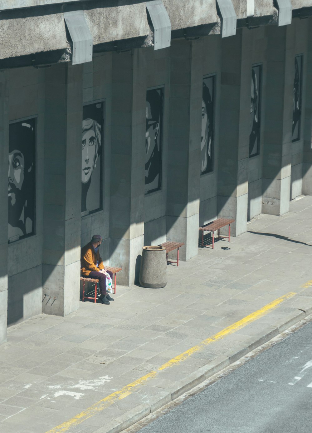 man in black and yellow jacket sitting on gray concrete bench