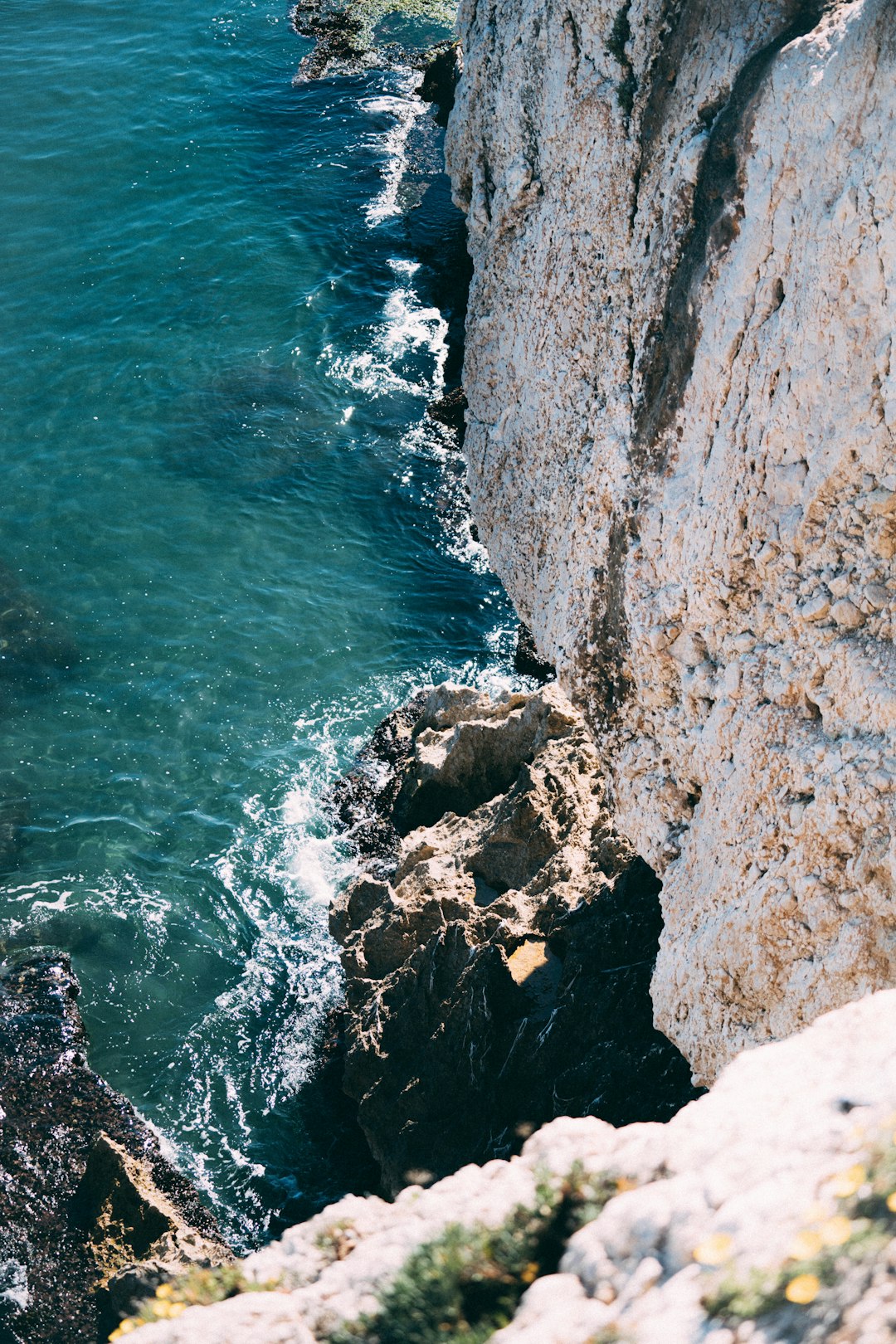 brown rocky mountain beside blue sea during daytime