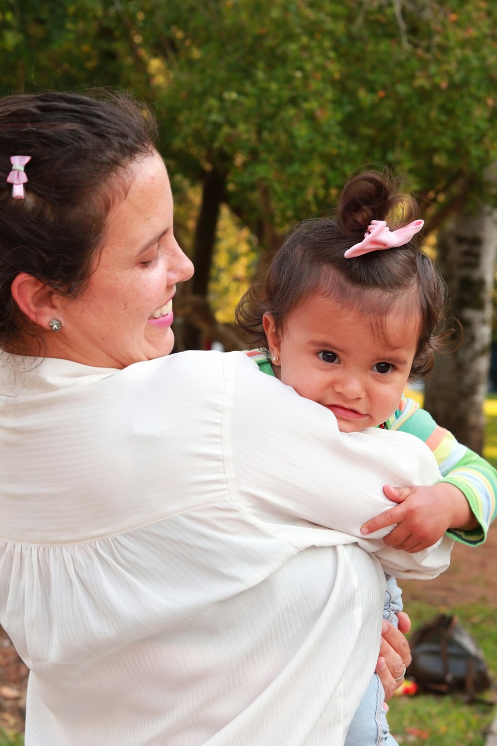 woman in white shirt carrying baby in green and white shirt