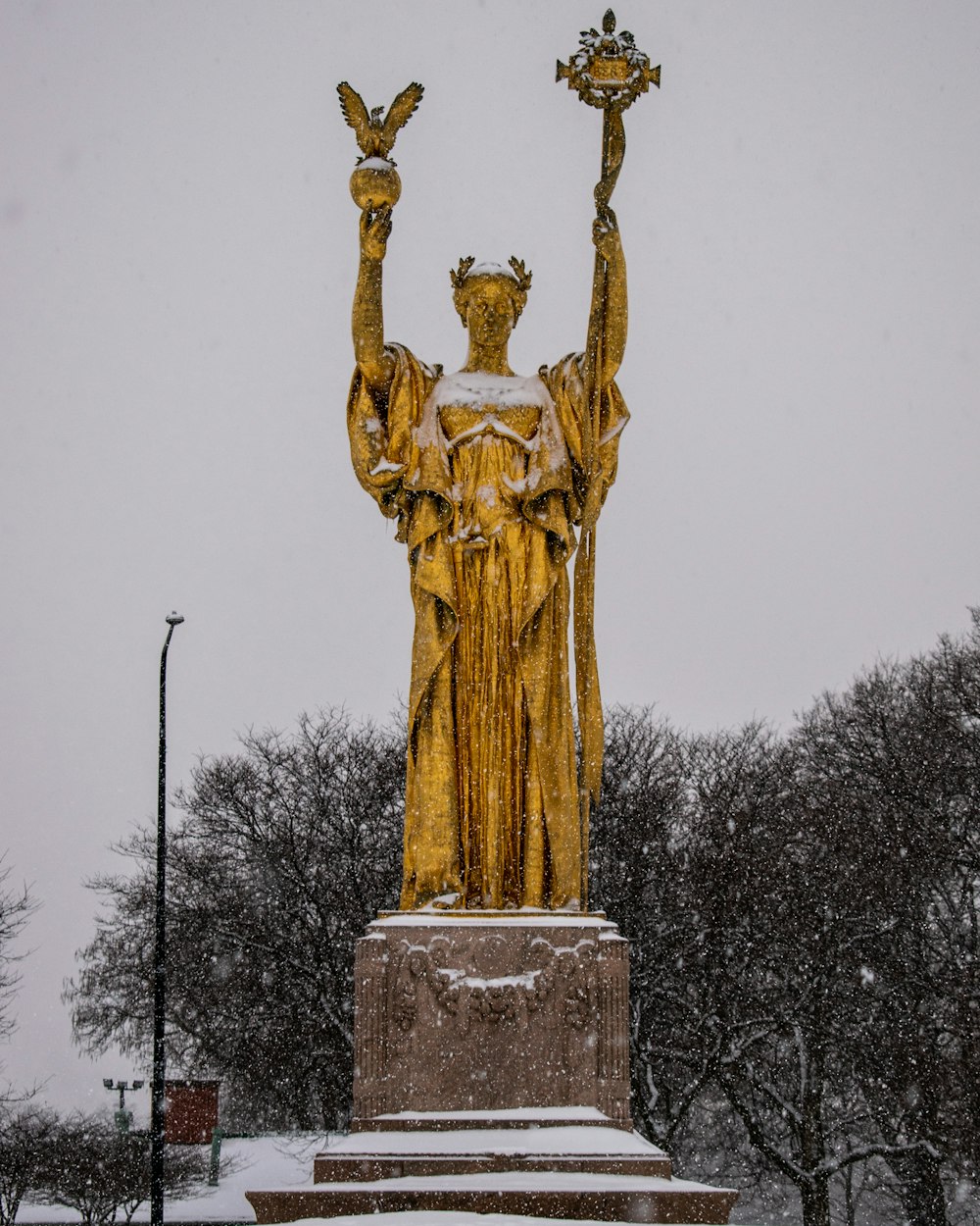 gold statue of man holding book