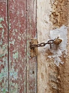Close-up of a rusty front door with chipped paint and a broken lock.