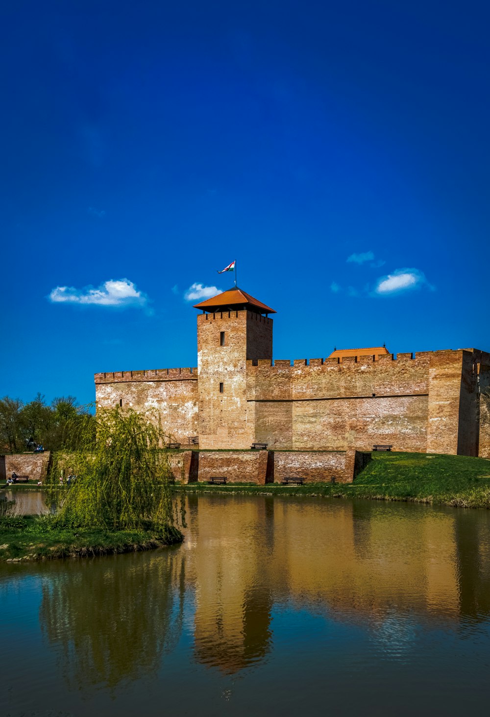 brown brick building beside river under blue sky during daytime