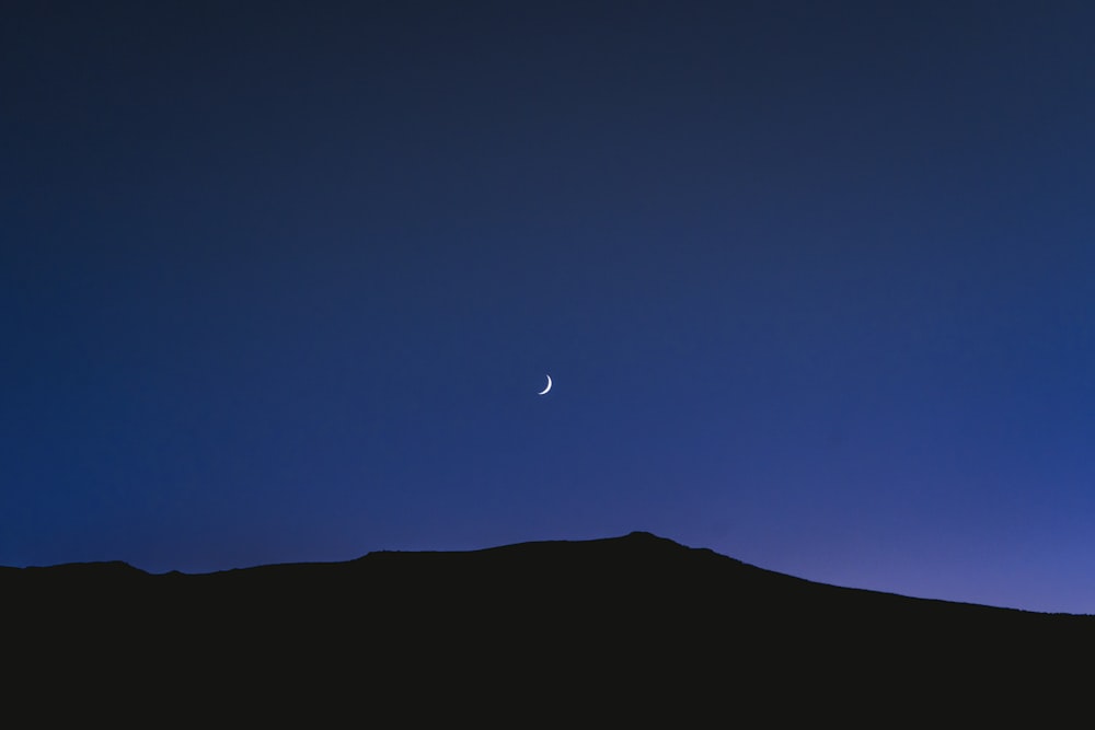 silhouette of mountain under blue sky during night time