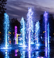 water fountain with lights turned on during night time