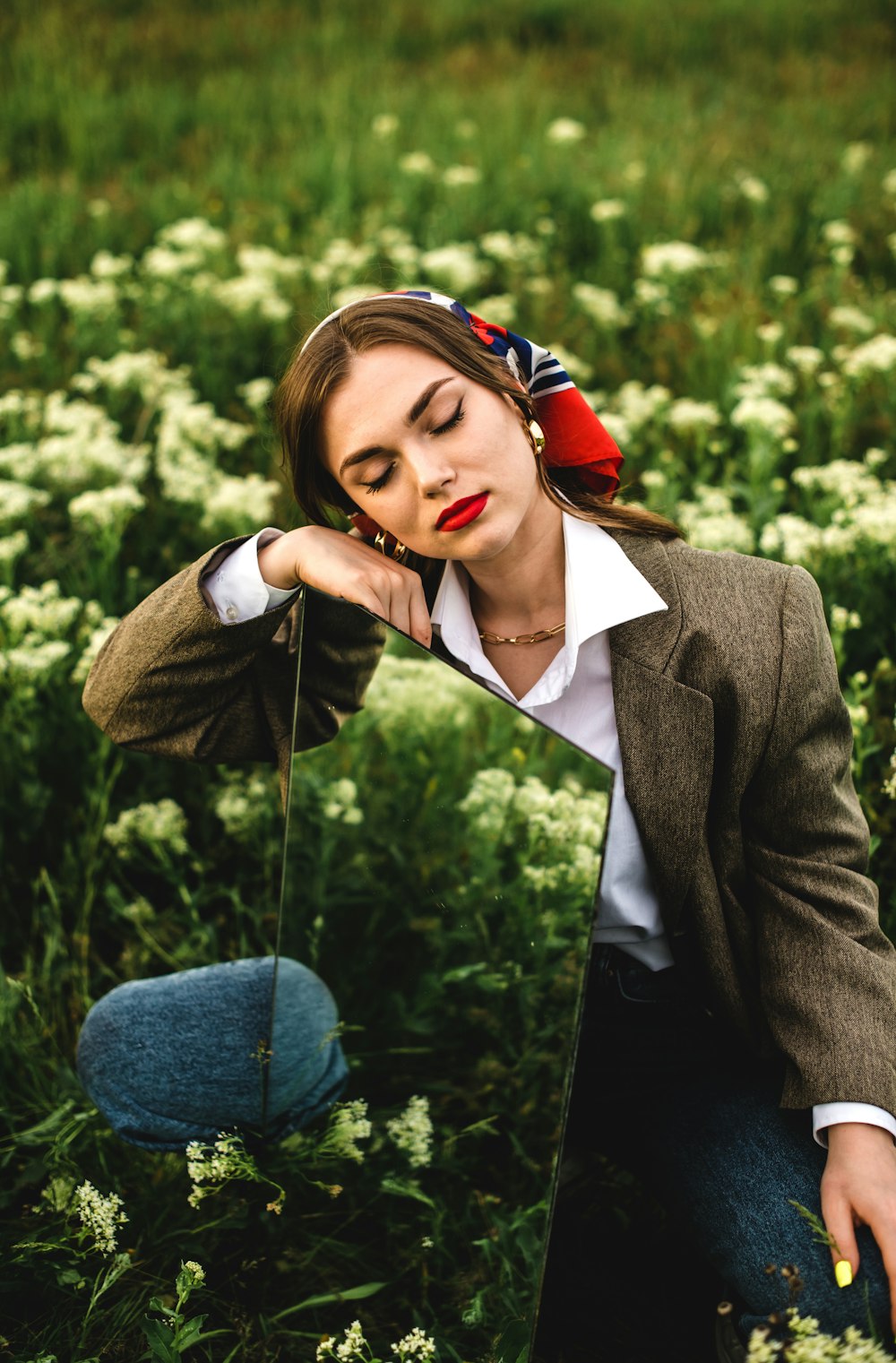 woman in black blazer and blue denim jeans holding red rose