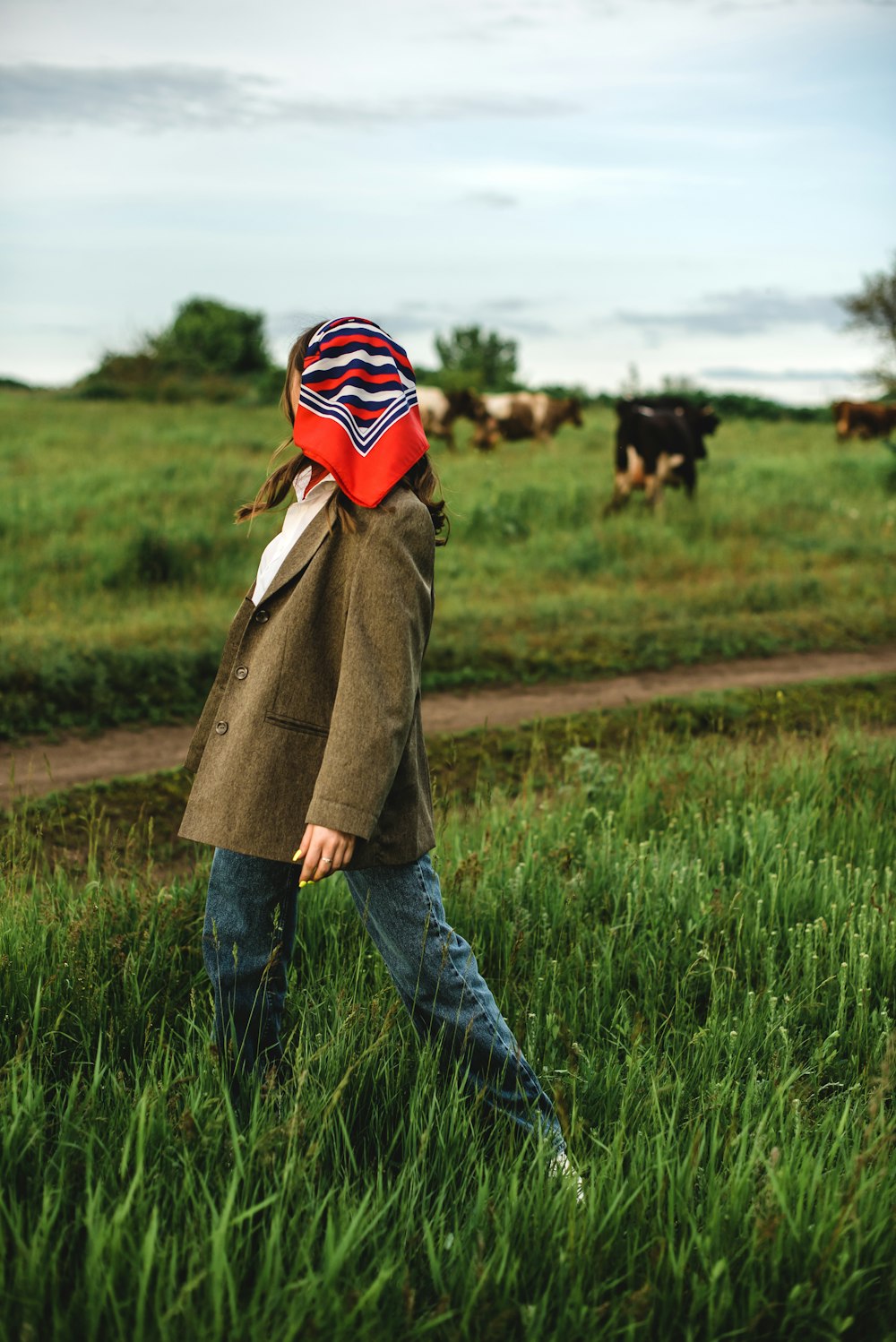 woman in brown coat standing on green grass field during daytime