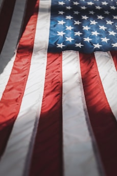 A close-up of a folded patriotic flag beside rugged military boots on wooden floor