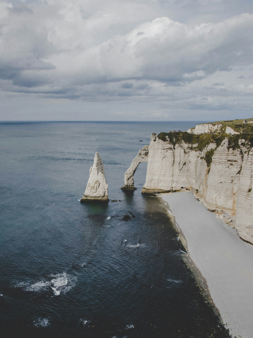 white rock formation on sea under white clouds during daytime