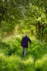 man in purple jacket walking on green grass field during daytime
