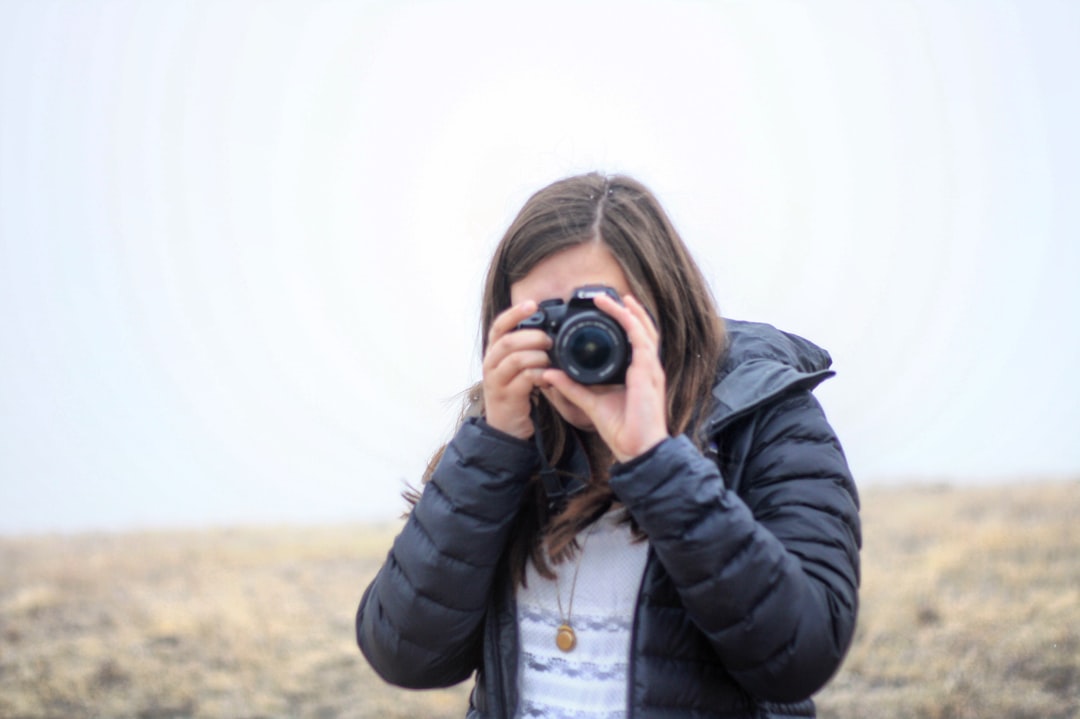 woman in black jacket holding black dslr camera