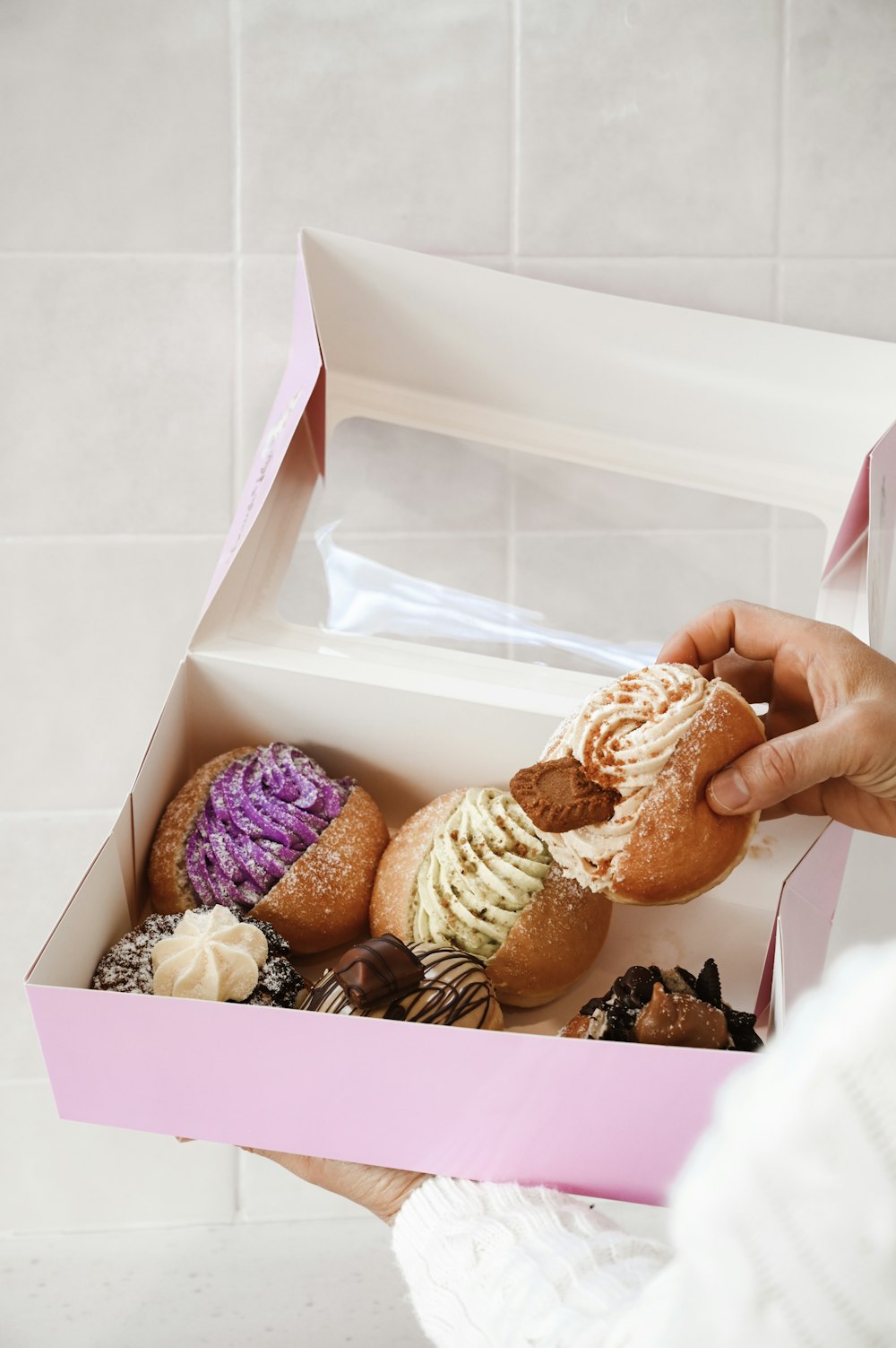 person holding box of doughnuts