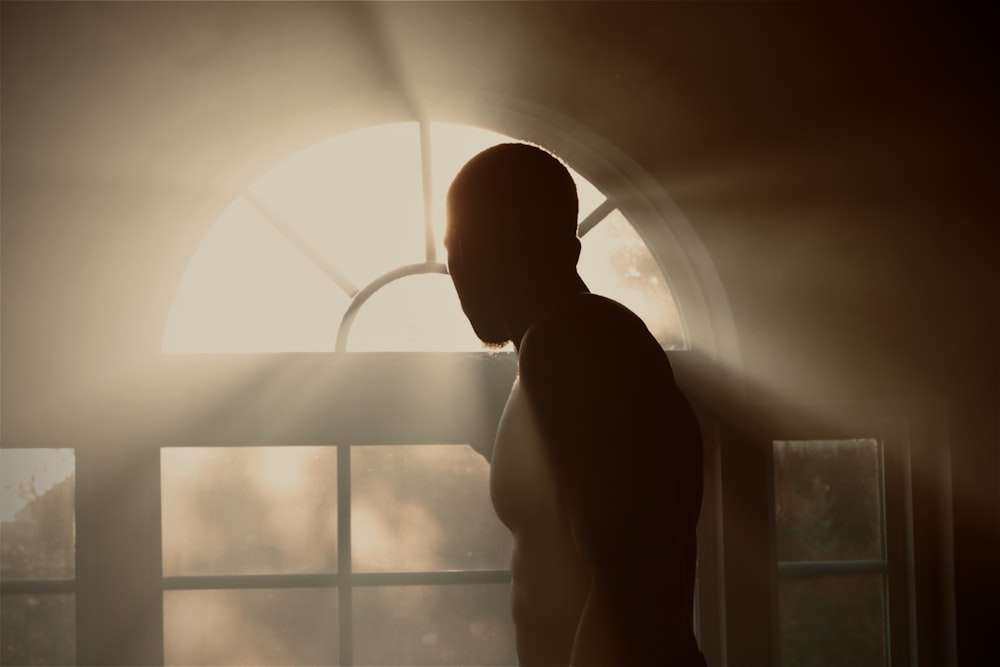 silhouette of man standing near window