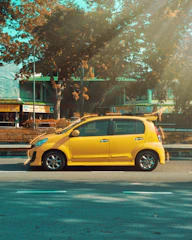 A happy passenger quickly getting into a modern yellow and black car in a sunny city street.