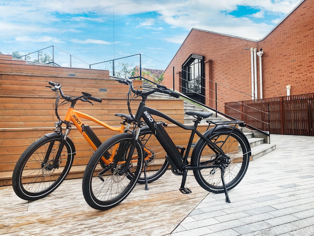 Bicicleta negra y marrón estacionada junto a un edificio de concreto marrón durante el día