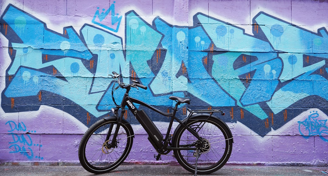 black bicycle parked beside blue and white wall