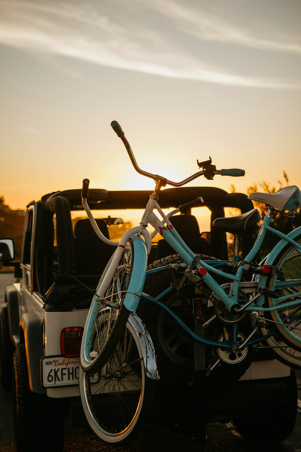 blue city bike parked beside white car during sunset