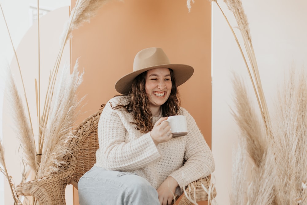 woman in white sweater and brown hat sitting on brown wooden chair