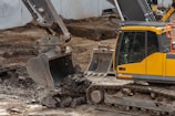 yellow and black excavator on brown soil